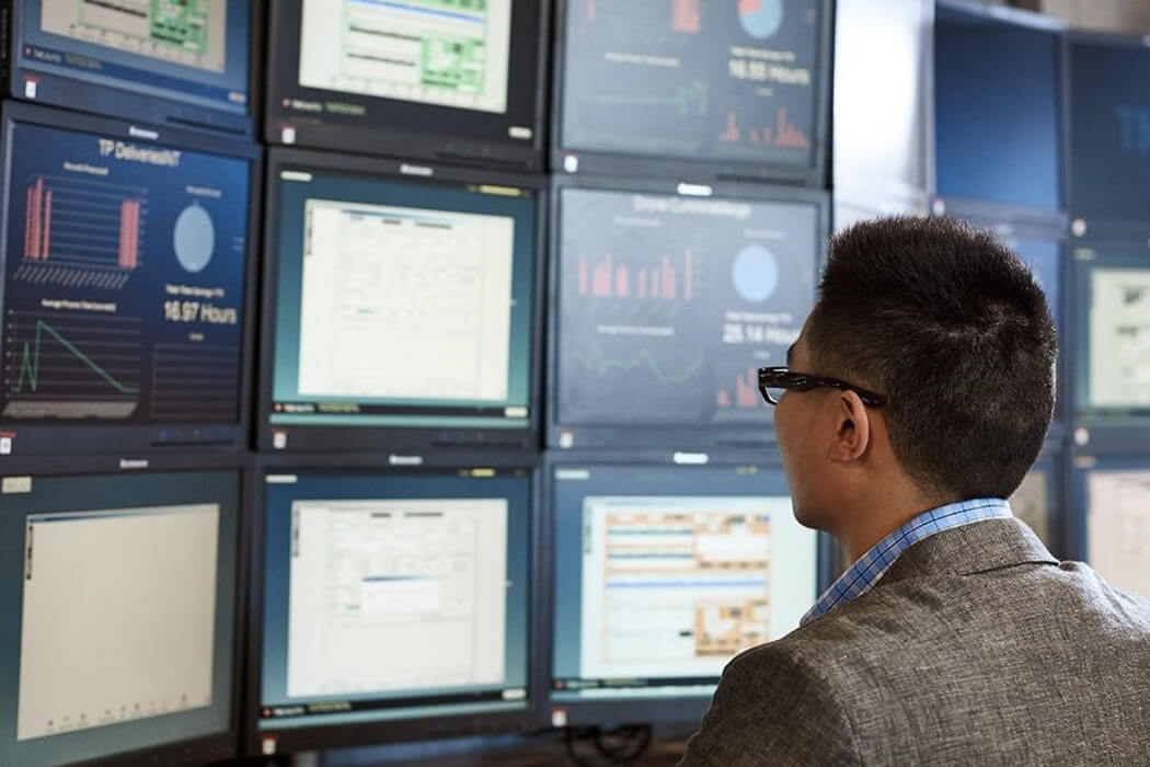 Person looking at computer screens on wall.